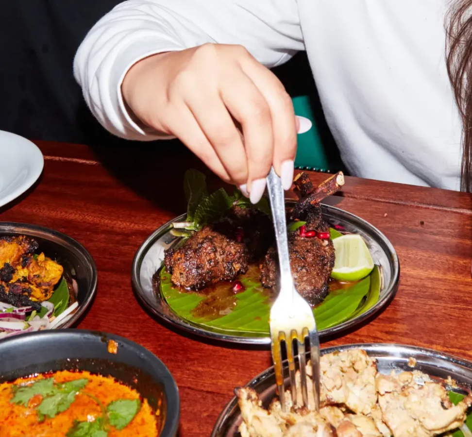 Hand serving a plated dish with a fork