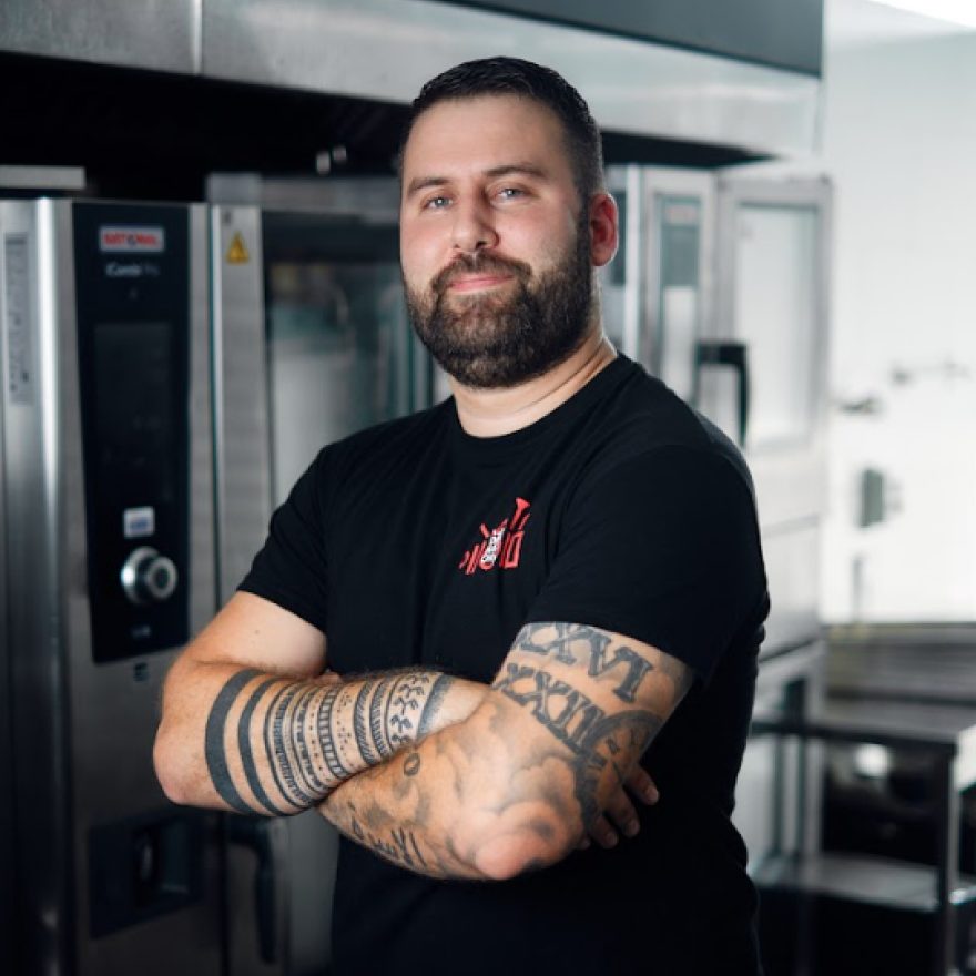 Head chef with tattooed forearms in a black T-shirt